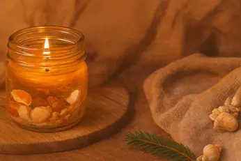 Warme gelbe Gelkerze in einem Glas mit Zimt und Tannenzweig – weihnachtliche Stimmung